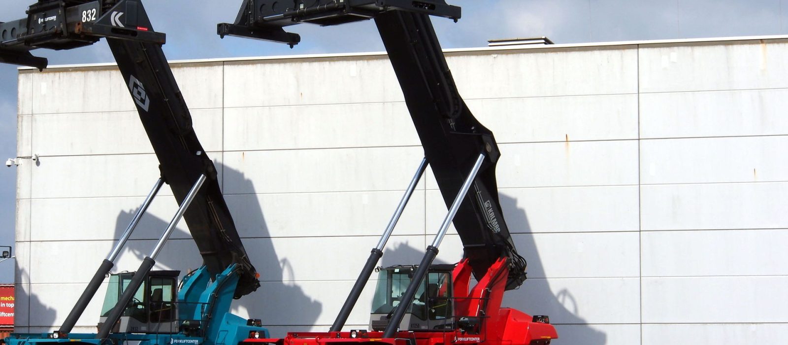 Two reach stackers standing beside a terminal building