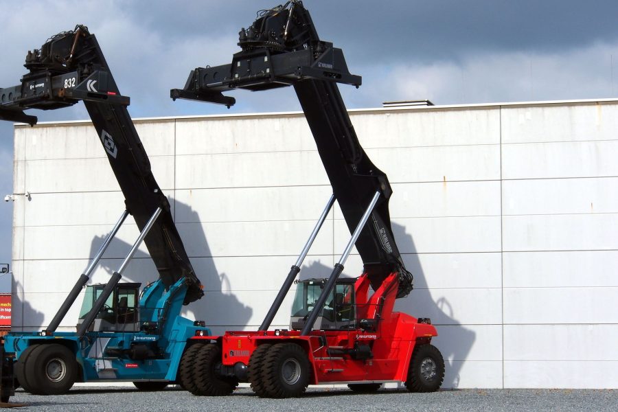Two reach stackers standing beside a terminal building
